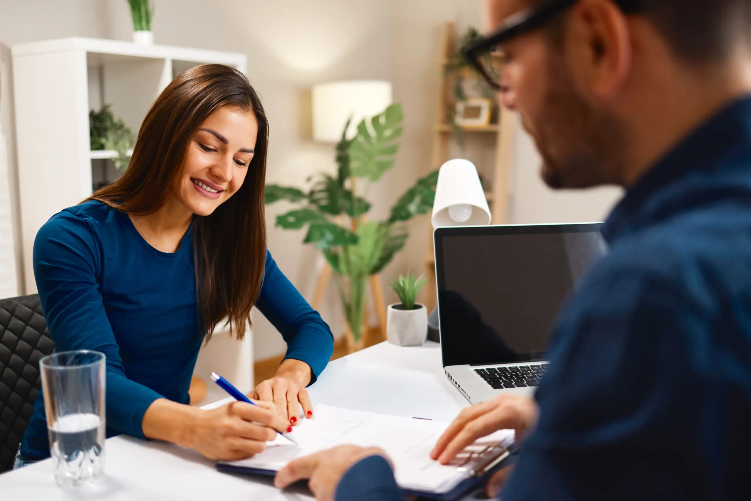 Woman signing contract with financial advisor at home office