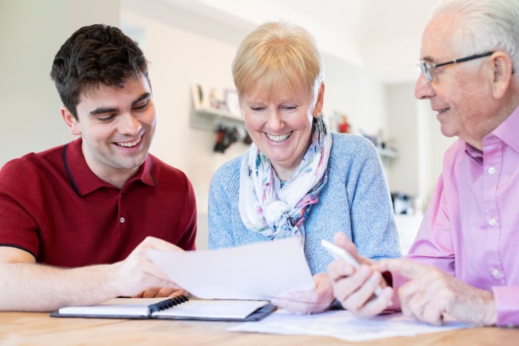 Young Man Helping Senior Couple With Financial Paperwork At Home